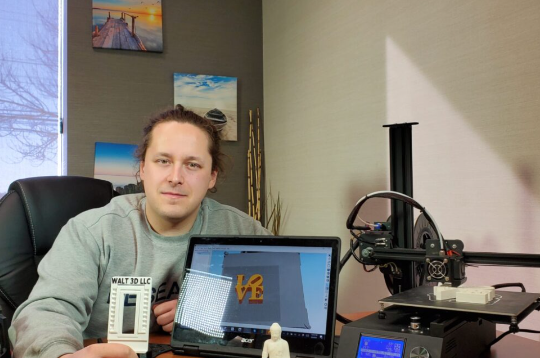 Brian Walt beside a 3D printer and computer workstation